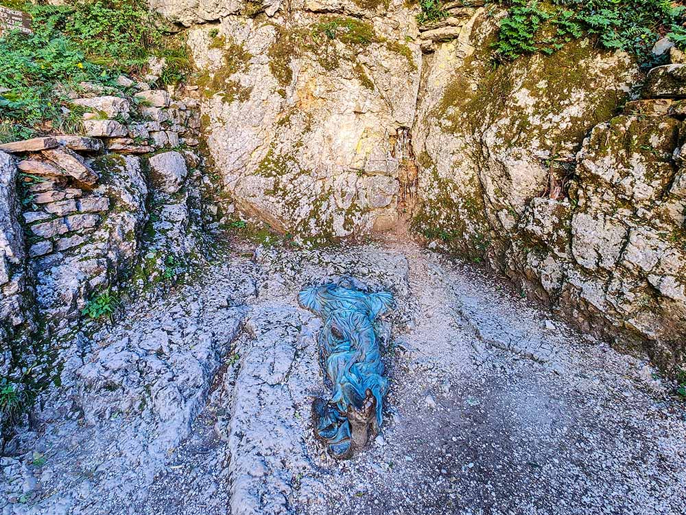 A statue depicts St. Francis of Assisi lying on the ground gazing toward the heavens at Eremo delle Carceri on Mount Subasio, Italy. (NCR photo/Brian Roewe)