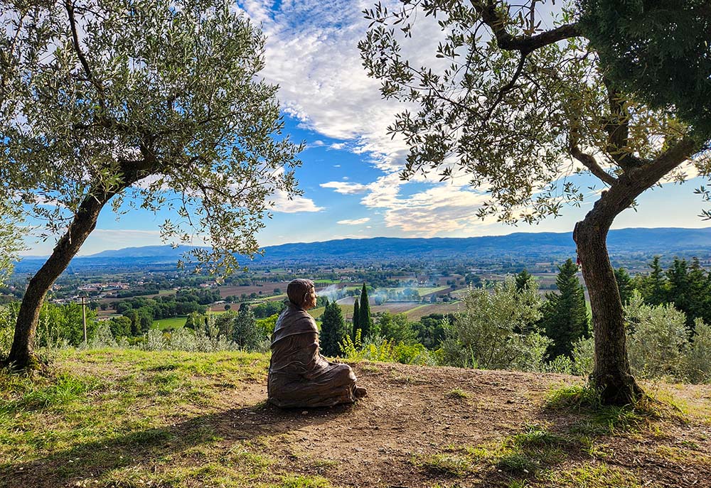 A bronze sculpture of St. Francis of Assisi looks out over the medieval Italian town outside the Church of San Damiano on Oct. 4, 2025. (NCR photo/Brian Roewe)