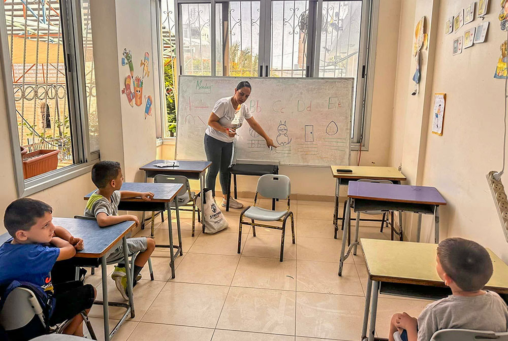 A teacher at Holy Family Parish's school in Gaza City is seen July 22, 2024, in a classroom with children as part of the St. Joseph educational project for the 150 Christian youth sheltering at the parish compound and at the nearby Greek Orthodox church compound. (OSV News/Courtesy of Gabriel Romanelli)