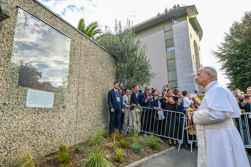 Before meeting with bishops representing the French bishops' conference, Pope Leo XIV stops for a moment at a plaque featuring a quotation from a survivor of abuse in Lourdes, France, Sept. 27, 2026. (CNS/Vatican Media)
