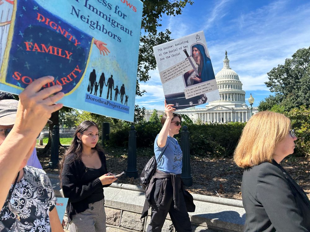 A protester holds a poster depicting the Seven Sorrows through the lens of modern immigrants' experiences during an event Sept. 15 in Washington. (Emma Cieslik)