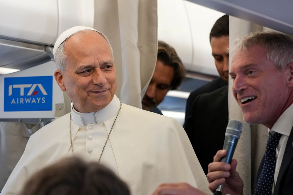 Pope Leo XIV looks on as Matteo Bruni, head of the Vatican press hall, speaks to journalists aboard the papal flight from Rome to Paris Sept. 25, 2026, at the start of his apostolic journey to France and visit to UNESCO. (CNS/Lola Gomez)