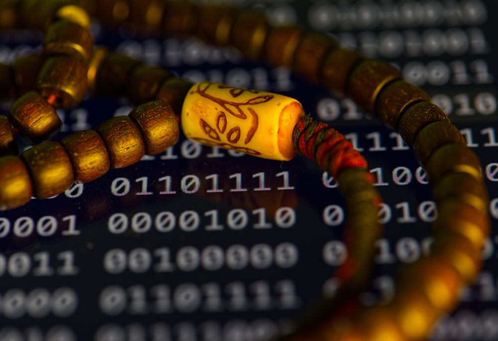 Prayer beads are photographed over a screen displaying binary code in Phoenix, Friday May 8, 2026. (AP photo/Dario Lopez-Mills)