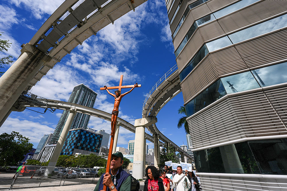 Ramon Ventura carries a crucifix as people walk from a downtown Miami Catholic church to the Miami Immigration Court to hold a prayer for immigrants, on the feast day of Mother Cabrini, patron saint of immigrants, Nov. 13, 2025. (AP/Rebecca Blackwell)