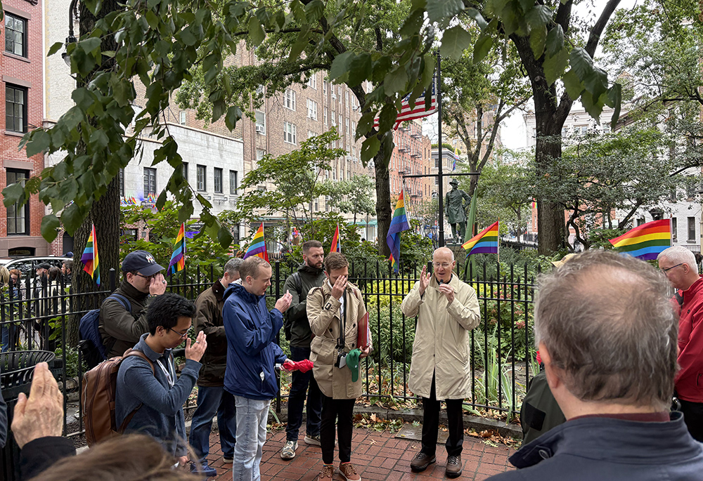 Jesuit Fr. James Martin blesses LGBTQ Catholics and other Catholic pilgrims during a moment of prayer and reflection Sept. 26 outside the Stonewall Inn, the historic bar considered the site of the start of the LGBTQ rights movement after riots in 1969. (NCR photo/Camillo Barone)