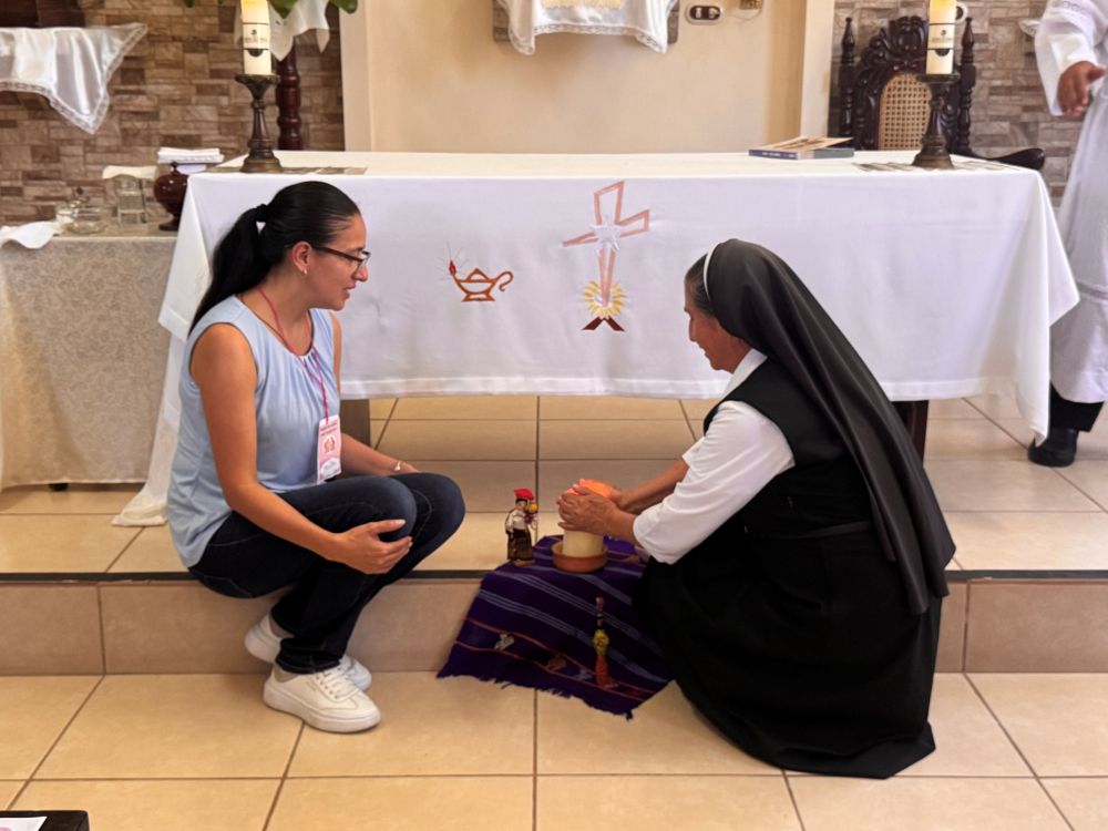 Sr. Indra Monterroso Padilla, of the Bethlemite Sisters, Daughters of the Sacred Heart of Jesus, lights a candle with laywoman Martha Calderon at a chapel in El Paraíso, El Salvador, where women religious and laywomen gathered Sept. 12, 2026, to keep the work of the synod alive. (GSR photo/Rhina Guidos)