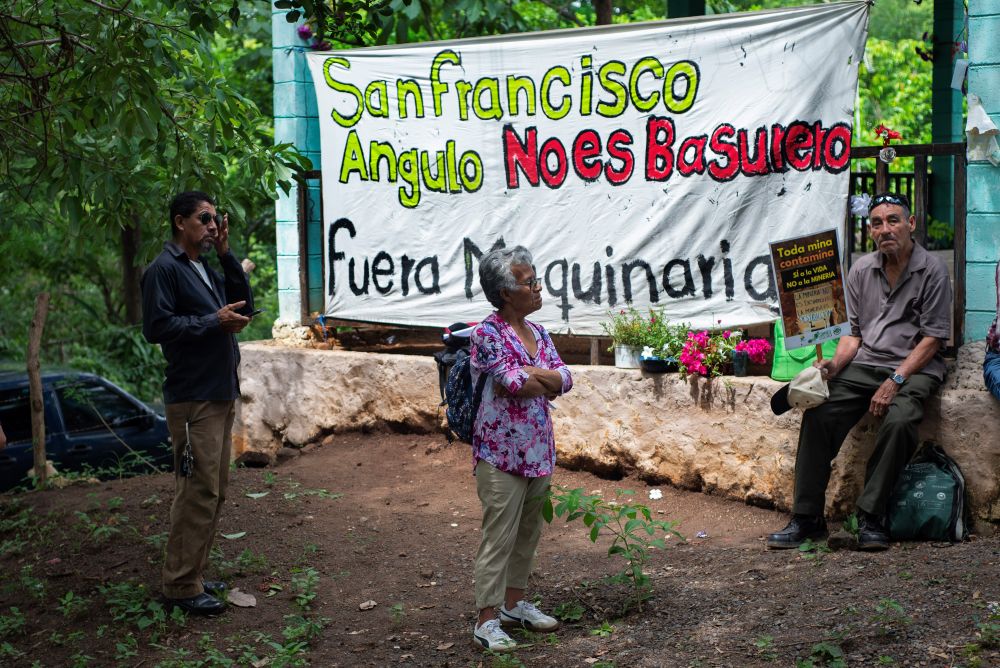 Residents of the San Francisco Angulo, El Salvador, community stand in front of a banner protesting pollution in the community on Sept. 26. (Lissette Lemus) 