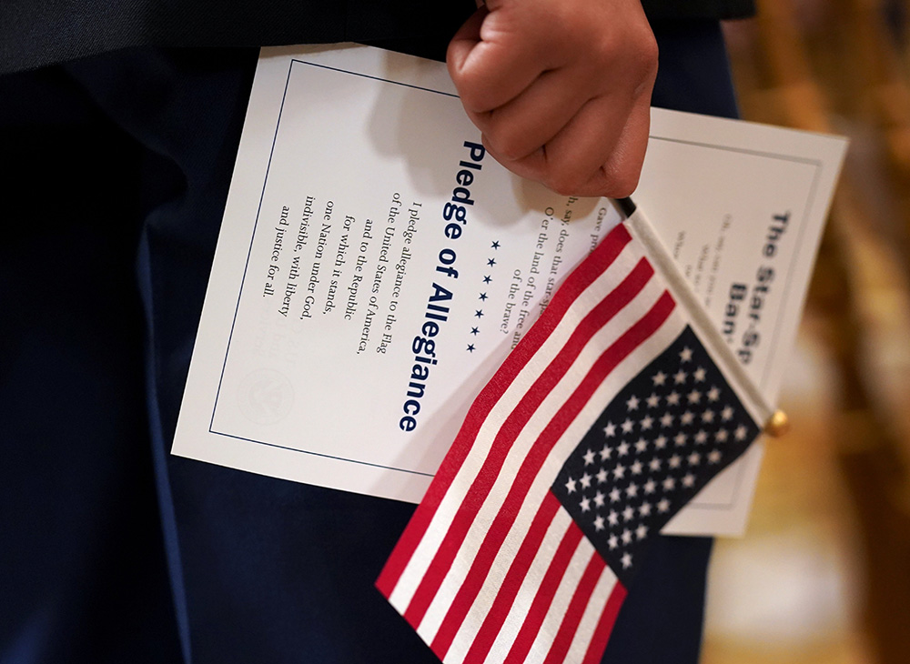 A U.S. flag and a copy of the Pledge of Allegiance are held during a naturalization ceremony in a 2021 file photo. (OSV News/Reuters/Kevin Lamarque)