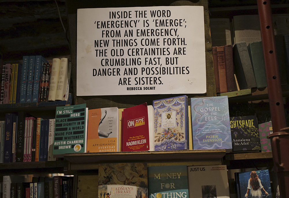 A panel on "Emergency" by Rebecca Solnit hangs on the book shelves of the English and American literature Shakespeare and Co. bookstore, in Paris, France, Nov. 05, 2020. (AP photo/Francois Mori)
