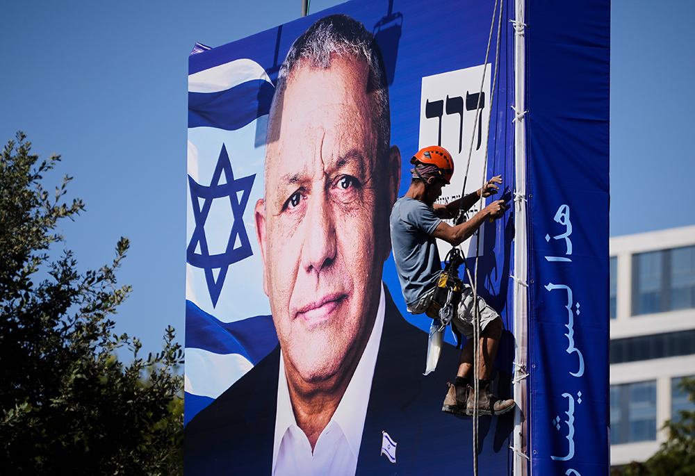 A worker hangs a campaign billboard featuring Gadi Eisenkot, leader of Yashar ("Straight") party, ahead of Israel's general election in Jerusalem, Oct. 22, 2026. (AP photo/Ohad Zwigenberg)