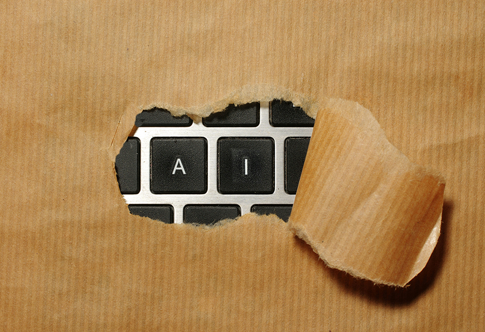 An illustration shows a package with wrapping torn away in the center, revealing a gray and black keyboard underneath. Through the tear the keys A and I are framed, spelling "AI."