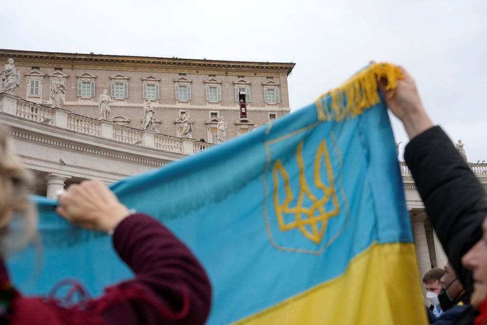 Ukrainian faithful hold their national flag as Pope Francis delivers the Angelus noon prayer from his studio window overlooking St. Peter's Square, at the Vatican, Feb. 20. (AP/Gregorio Borgia)