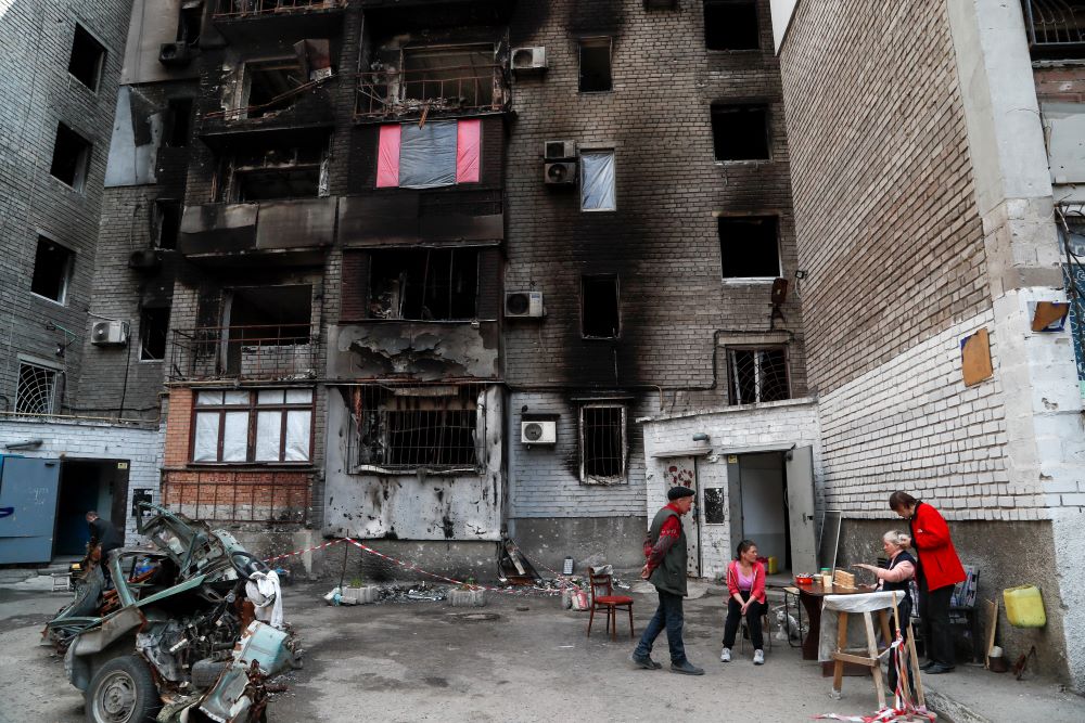 Local residents gather outside an apartment building damaged during Ukraine-Russia conflict in the southern port city of Mariupol, Ukraine, May 15. (CNS/Reuters/Alexander Ermochenko)