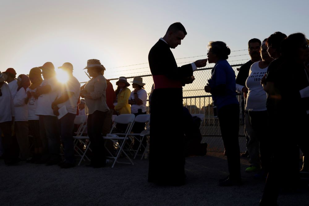 Migrants watching Pope Francis' Mass in Juarez, Mexico, from a levee along the banks of the Rio Grande in El Paso, Texas, take part in Communion, Feb. 17, 2016.
