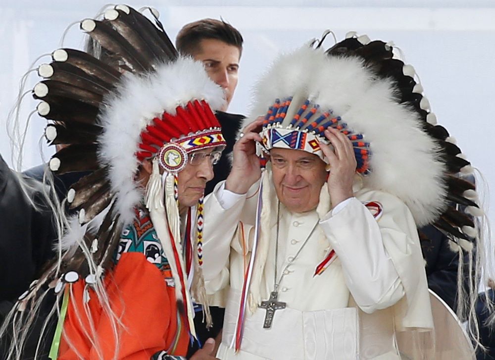 Pope Francis adjusts a traditional Indigenous headdress during a meeting with First Nations, Métis and Inuit communities at Maskwacis, Alberta, July 25. During a weeklong visit to Canada, the pope met with Indigenous groups.