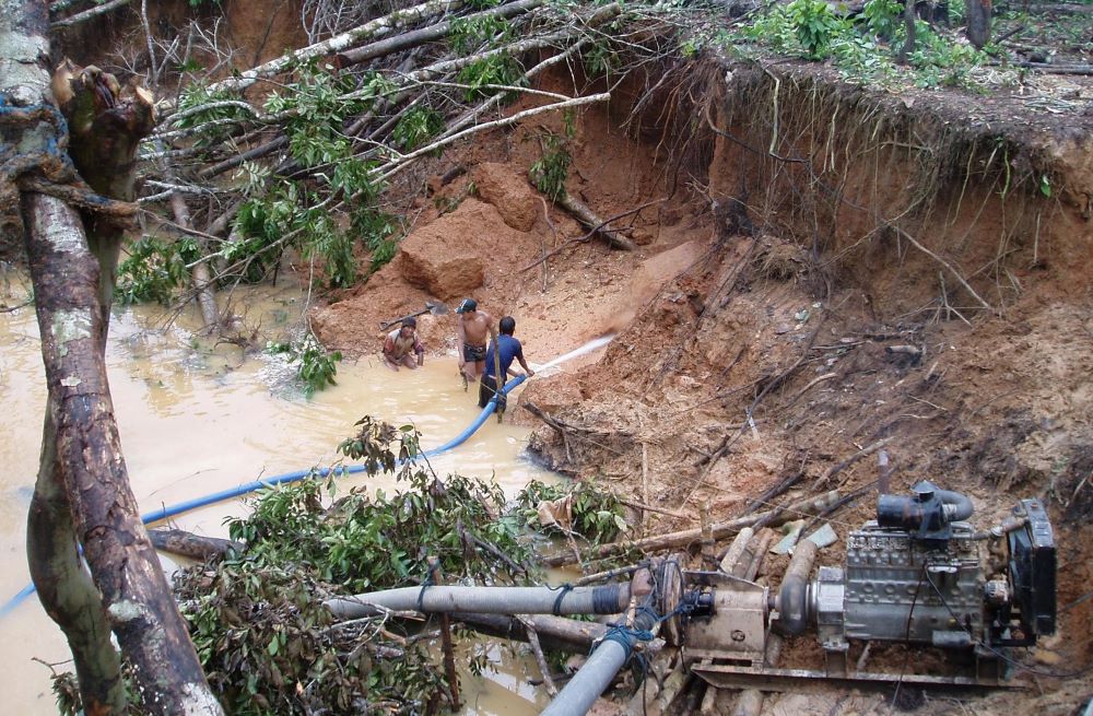 Miners use high-pressure hoses to blast away soil in order to sluice it for gold in Puerto Maldonado, Peru, in March 2006. A new report documents an increase in violence and land grabs in 2021. (CNS/Xavier Arbex)