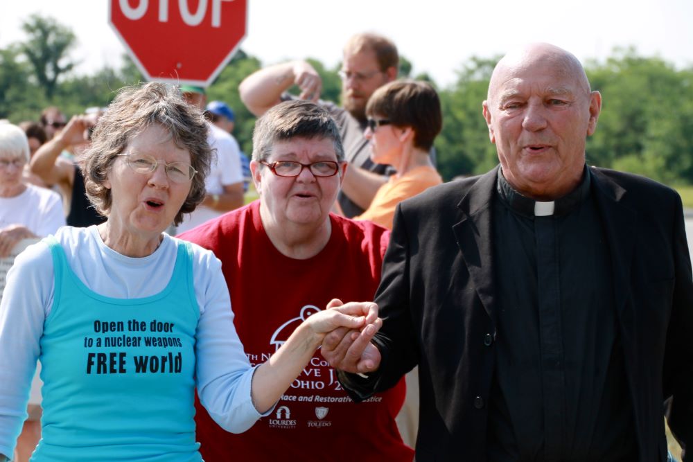 Oblate Fr. Carl Kabat, right, holds the hand of organizer Jane Stoever, left, as they lead protesters across the property line at the National Nuclear Security Administration's Kansas City Plant July 13, 2013, in Kansas City, Missouri. 