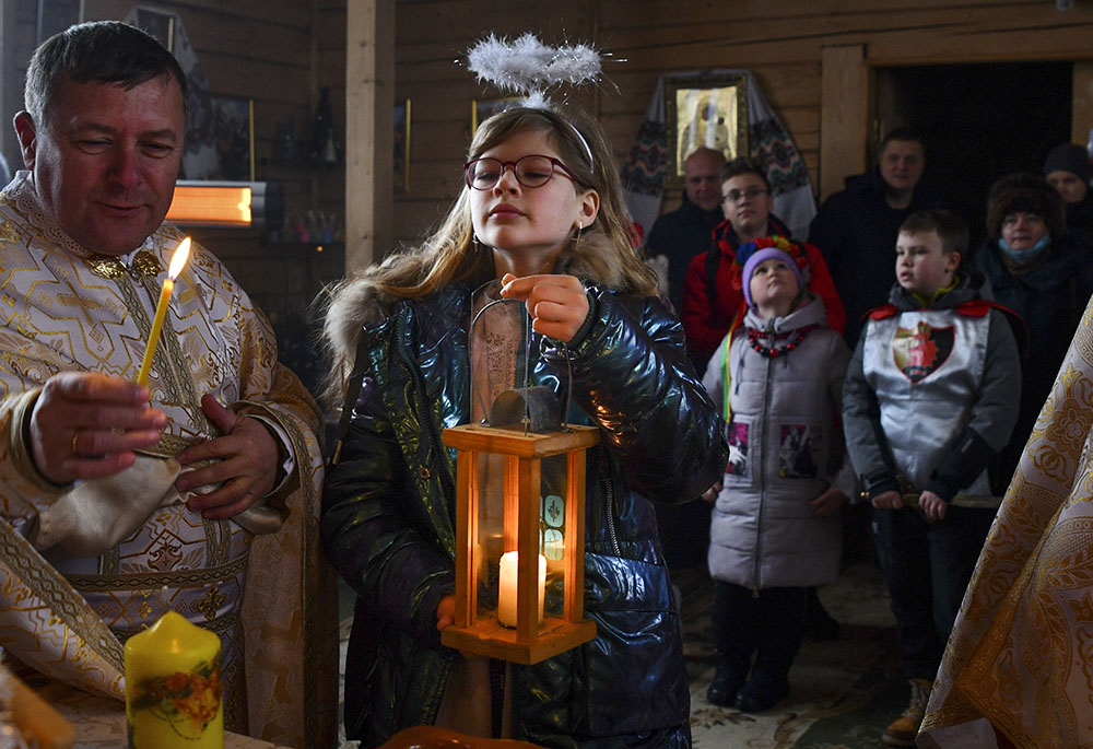 A girl holds a candle during a Christmas service at the Ukrainian Greek Catholic Church of the Holy Prophet Elijah in Kramatorsk, not far from a front line with Russia-backed separatists in eastern Ukraine, Dec. 25, 2021. (AP/Andriy Andriyenko)