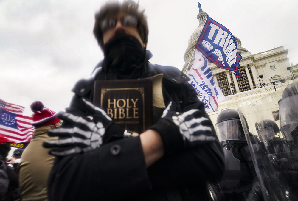 In this Jan. 6, 2021, file photo, a man holds a Bible as Trump supporters gather outside the Capitol in Washington. (AP photo/John Minchillo) In this Jan. 6, 2021, file photo, a man holds a Bible as Trump supporters gather outside the Capitol in Washington. (RNS/AP photo/John Minchillo)