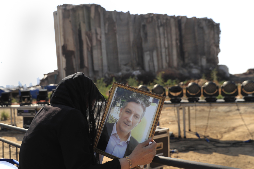 A relative of a victim who was killed in the massive blast last year at the Beirut port reacts and holds his portrait as she attends an Aug. 4 mass held to commemorate the first year anniversary, at the Beirut port, Lebanon. (AP/Hussein Malla)