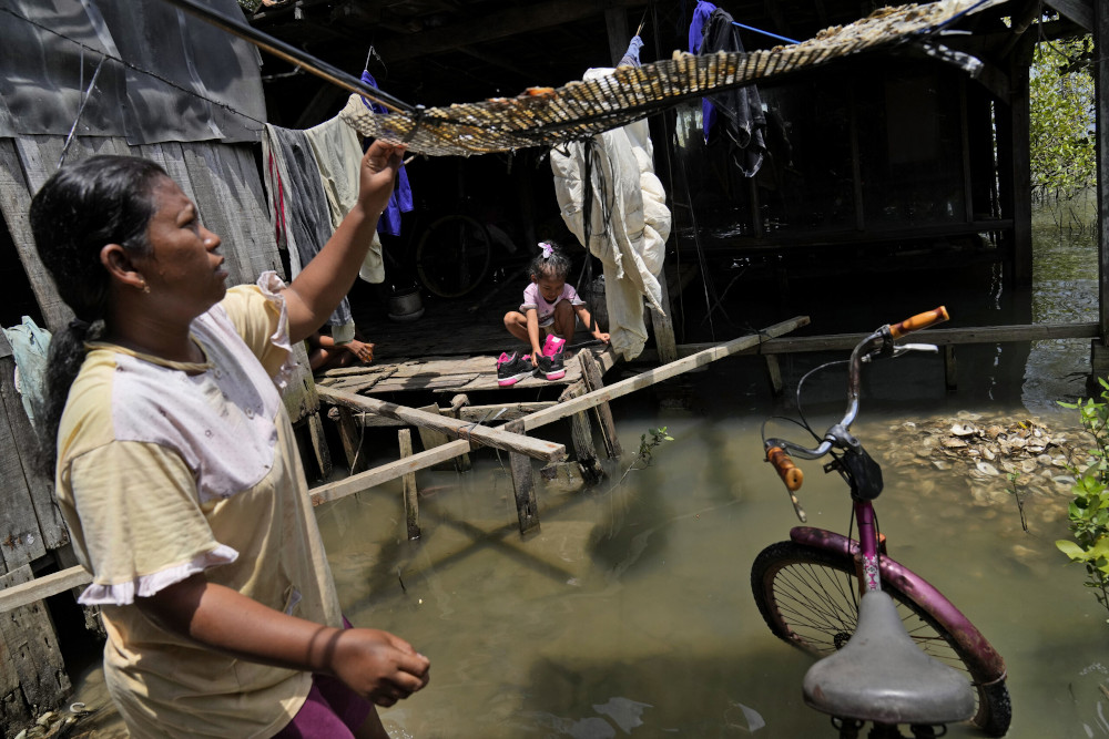 Nia Riningsih, one of few residents who stayed behind after most of her neighbors left due to the rising sea levels that inundated their neighborhood on the northern coast of Java Island, in Mondoliko village, Central Java, Indonesia, Nov. 7, 2021. (AP)