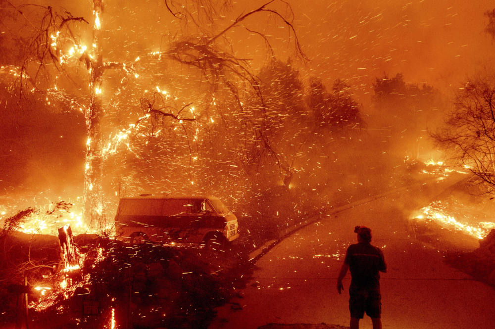 Bruce McDougal watches embers fly over his property as the Bond Fire burns through the Silverado community in Orange County, California, on Dec. 3, 2020. (AP Photo/Noah Berger, File)