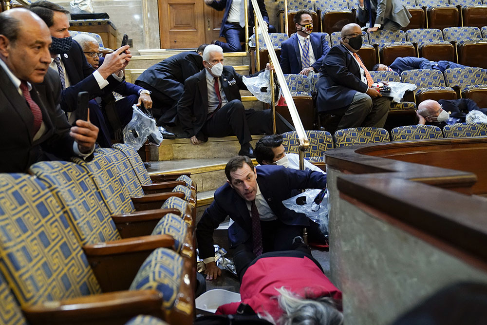 People shelter in the House gallery as protesters try to break into the House chamber at the U.S. Capitol on Jan. 6 in Washington. (AP Photo/Andrew Harnik) People shelter in the House gallery as protesters try to break into the House chamber at the U.S. Capitol on Jan. 6 in Washington. (AP Photo/Andrew Harnik)