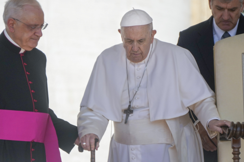 Pope Francis is helped by his aide Msgr. Leonardo Sapienza, left, as he walks with a cane to his weekly general audience in St. Peter's Square at the Vatican June 1. (AP/Gregorio Borgia)