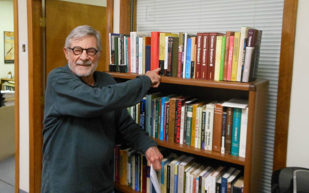 Richard Sipe in the offices of BishopAccountability.org points to a collect of his books that he gave to the church watchdog organization. (Courtesy of Fr. Tom Doyle)