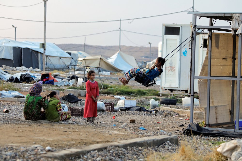 A girl near Mosul, Iraq, plays on a makeshift swing at Hammam Al-Alil camp where displaced Iraqis were preparing to be evacuated Nov. 10. (CNS/Reuters/Abdullah Rashid) 