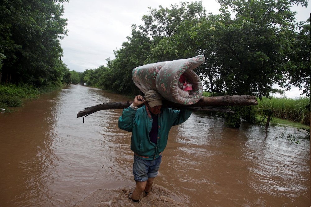 A man carries his belongings through a flooded road in Marcovia, Honduras, Nov. 18, after the passing of Hurricane Iota. (CNS/Reuters/Jorge Cabrera)