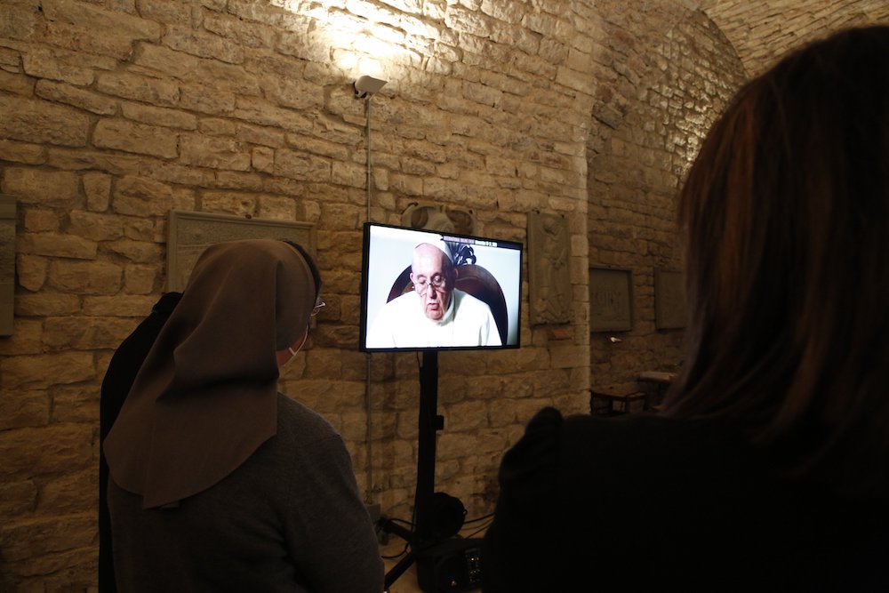 People in Assisi, Italy, watch as Pope Francis speaks in a video message presented Nov. 21 during the "Economy of Francesco" virtual meeting. (CNS/Economy of Francesco)