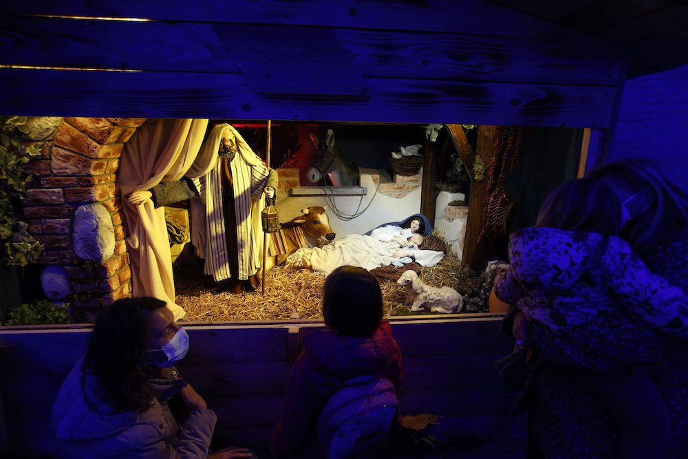 Family members visit the "100 Nativity Scenes at the Vatican" exhibit under the colonnade in St. Peter's Square at the Vatican Dec. 14. (CNS/Paul Haring)