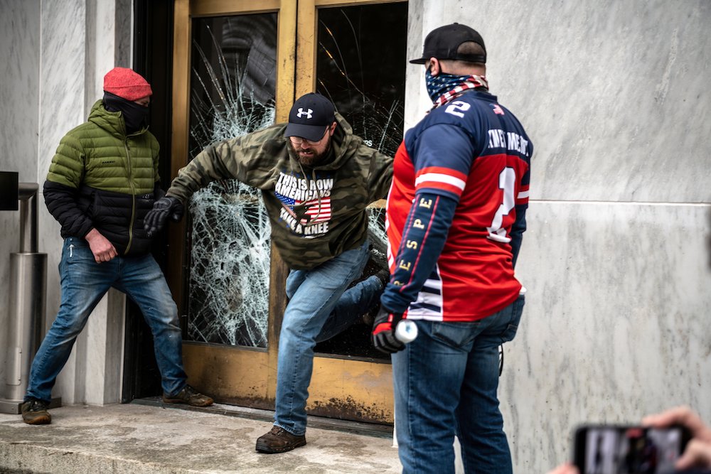 Protesters in Salem, Oregon, break the door to the state capitol building during a Dec. 21 protest against restrictions to prevent the spread of coronavirus disease. (CNS/Reuters/Mathieu Lewis-Rolland)