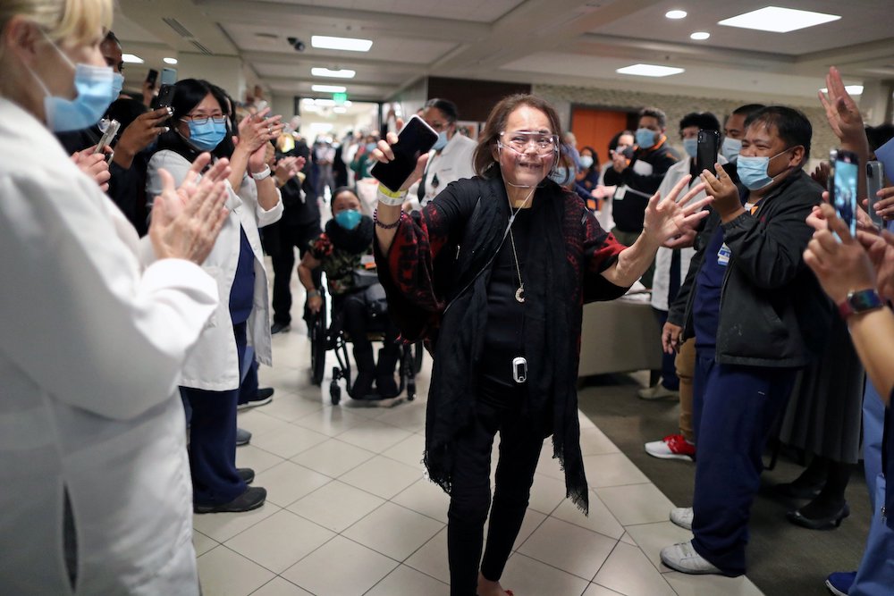 Merlin Pambuan, an intensive care unit nurse, is cheered by hospital staff at Dignity Health – St. Mary Medical Center in Long Beach, California, Dec. 21, as she walks out of the hospital where she spent eight months with COVID-19. (CNS/Reuters/Lucy Nicho