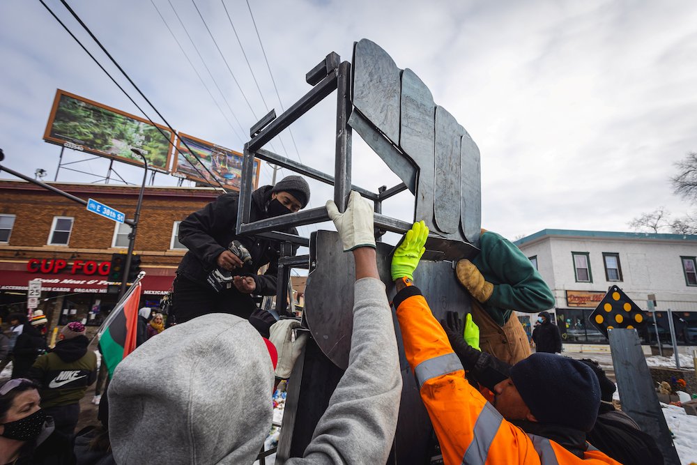 Artists and community members in Minneapolis help erect a new fist statue Jan. 18, 2021, to replace the old one in the square where George Floyd, a Black man, died after a white police officer knelt on his neck for nearly nine minutes. (CNS/Reuters/Ben Ho