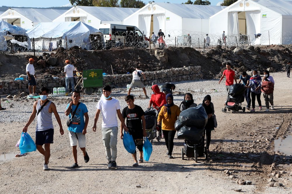 Migrants walk with their belongings as they make their way to the Kara Tepe refugee camp on the Greek island of Lesbos Oct. 14. (CNS/Reuters/Elias Marcou)
