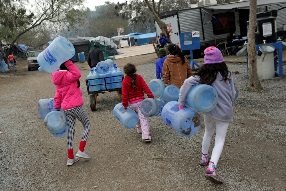 Children carry empty water containers inside a migrant encampment in Matamoros, Mexico, Feb. 18, 2021. (CNS/Reuters/Daniel Becerril) Children carry empty water containers inside a migrant encampment in Matamoros, Mexico, Feb. 18, 2021. (CNS/Reuters/Daniel Becerril)