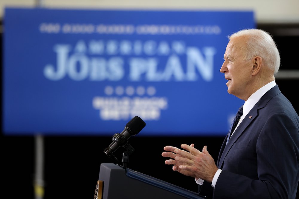Joe Biden profile at podium with sign in backgrouond "American Jobs Plan"