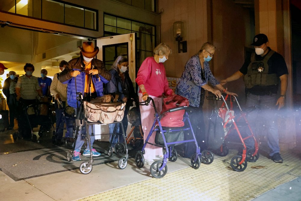 Residents of the Oakmont Gardens retirement community in Santa Rosa, California, use wheeled walkers to carry some belongings as they are evacuated by bus during the fast-moving Shady Fire Sept. 28. (CNS/Reuters/Stephen Lam)