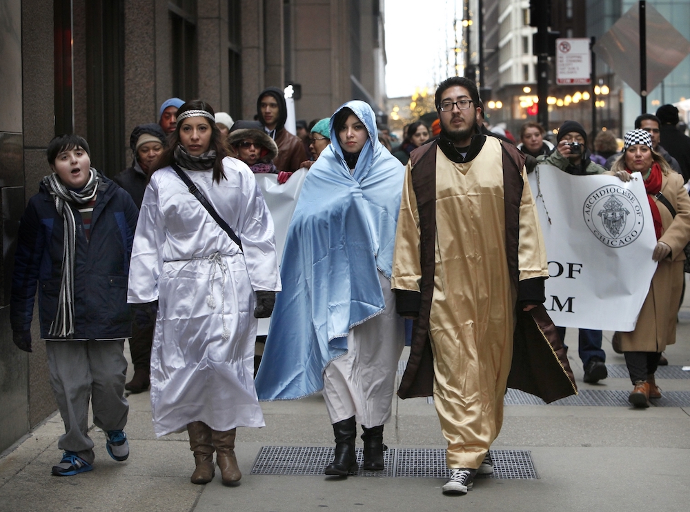Ivette Contreras, dressed as an angel, and Yazmin Diaz and Xavier Diaz, from St. Gall Parish in Chicago, portray Mary and Joseph during a Christmastime "posada" through the streets of Chicago Dec. 19, 2014. (CNS/Catholic New World/Karen Callaway)
