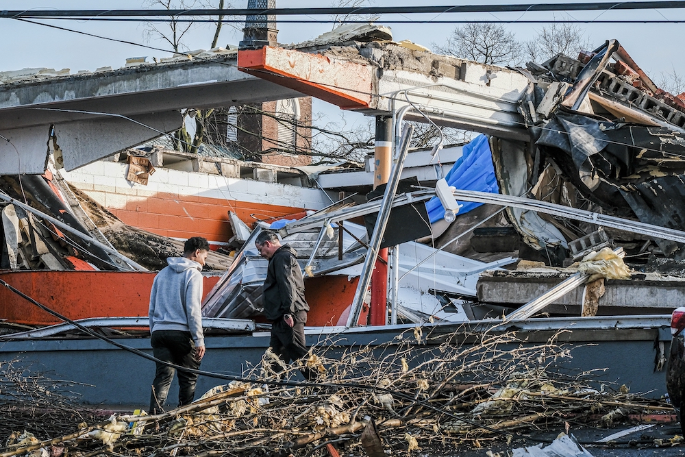 The steeple of the Church of the Assumption is seen in the background as neighbors clean up debris left in a tornado's wake in Nashville, Tennessee, March 3, 2020. (CNS/Tennessee Register/Rick Musacchio)