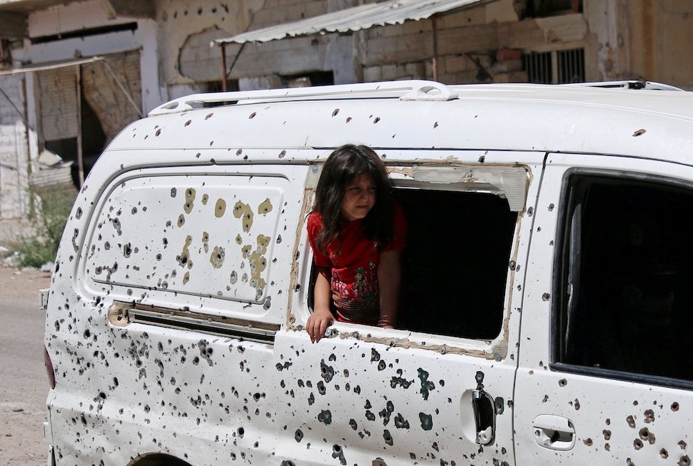 A girl in Daraa, Syria, looks out from a bullet-riddled bus July 9, 2017. Syria's civil war has now entered its 10th year. (CNS/Reuters/Alaa Al-Faqir)