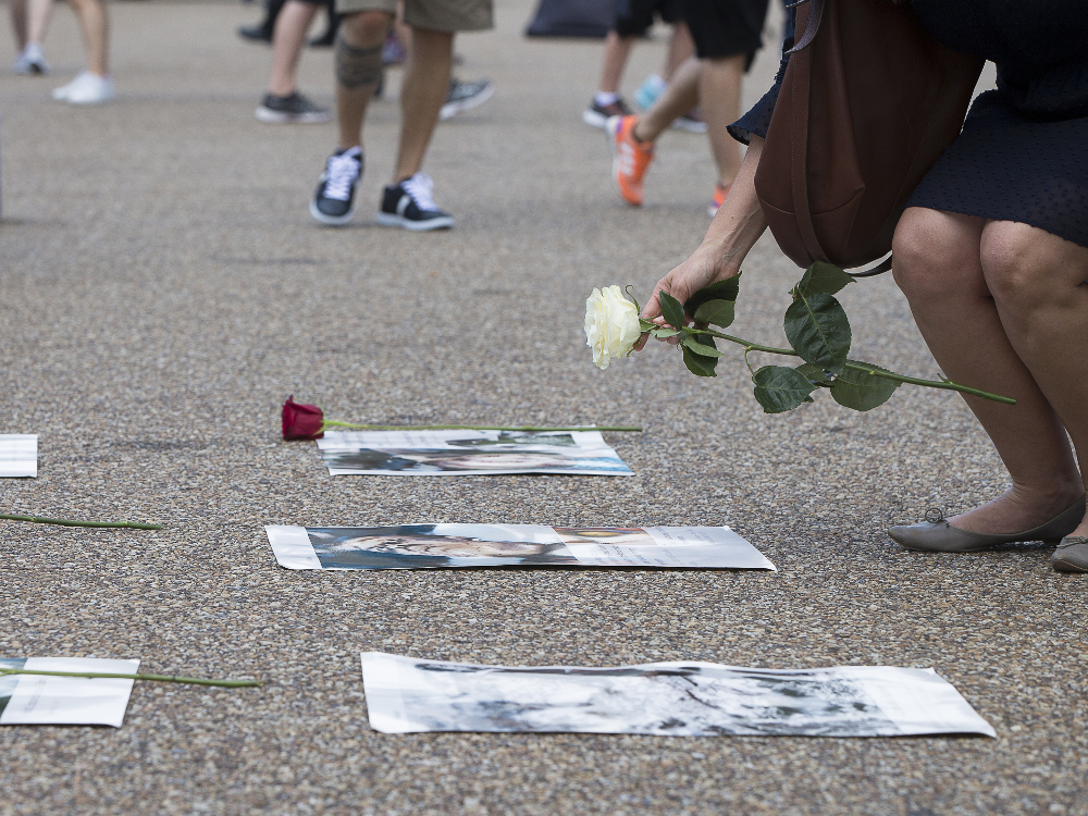 A woman places a rose on the photo of an atomic bomb victim in Washington during a Catholic prayer service of repentance near the White House Aug. 9 for the use of nuclear weapons on Japan during World War II. (CNS/Tyler Orsburn)