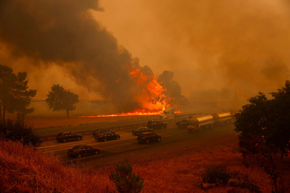 Motorists on Interstate 80 drive past flames drive past flames from the LNU lighting complex fire near Vacaville, CA, on Aug. 19, 2020. (CNS photo/Stephen Lam, Reuters)