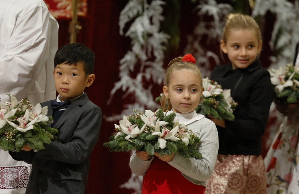 Children carry flowers to place at a figurine of the baby Jesus as Pope Francis celebrates Christmas Eve Mass in St. Peter's Basilica at the Vatican Dec. 24, 2017. (CNS/Paul Haring) Children carry flowers to place at a figurine of the baby Jesus as Pope Francis celebrates Christmas Eve Mass in St. Peter's Basilica at the Vatican Dec. 24, 2017. (CNS/Paul Haring)