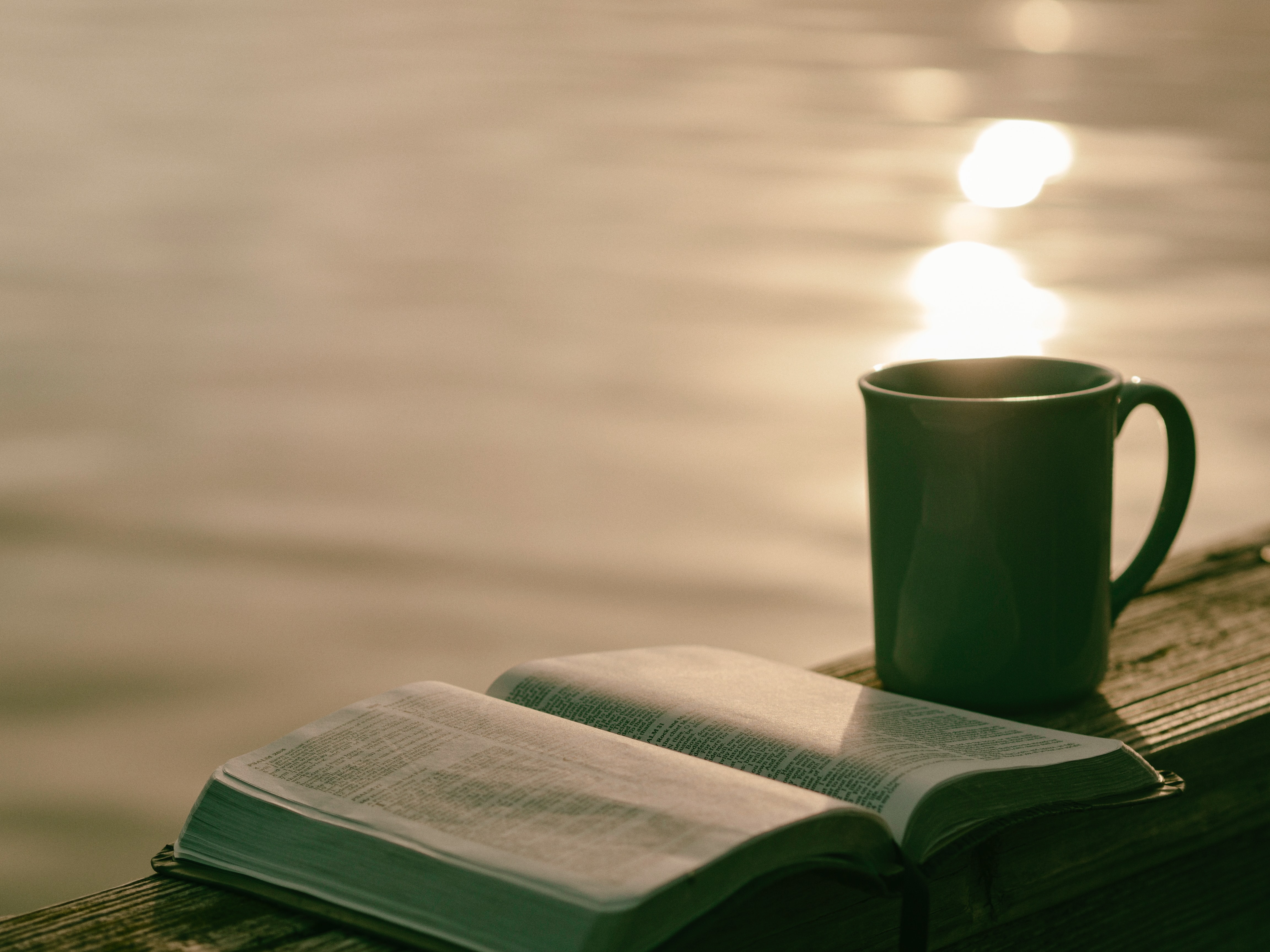 Coffee cup sits next to open Bible.