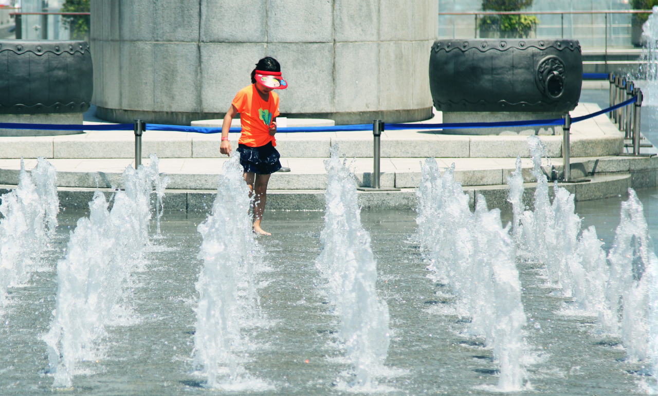 Child playing in a fountain with a sprinkler