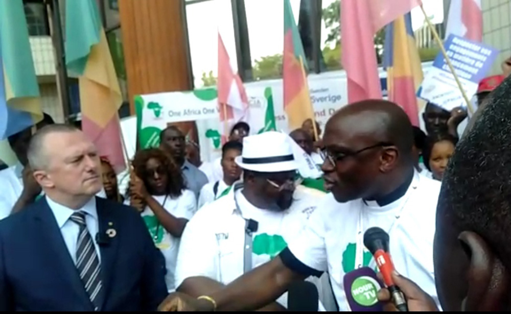 The Rev. Ezekiel Lesmore, right, program director for the All Africa Conference of Churches, speaks to Gabon environment minister Lee White, left, during a peaceful demonstration in Libreville, Gabon, Aug. 27, ahead of Africa Climate Week. (Teresia Gitau)