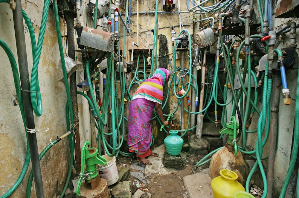 A woman uses a hand pump to fill a container with drinking water in Chennai, India. (CNS photo/P. Ravikumar, Reuters)